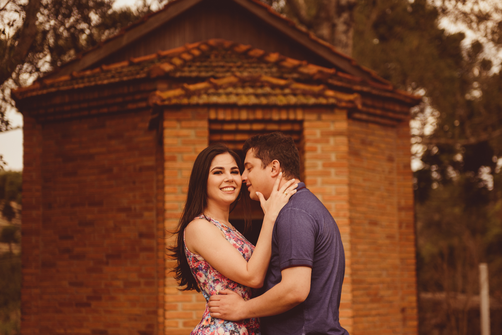 Casal em ensaio de pré-wedding em frente à capela de tijolos